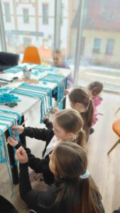 dzieci splatają sznurek do makramy