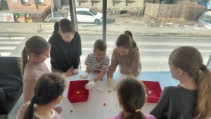 dzieci próbują przenieś pianki za pomocą kubeczków