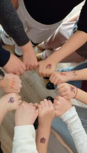 uczestnicy chwytają się za kciki. Na dłoni prowadzący ma napis ferie 2026