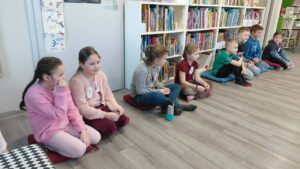 dzieci siedzą na poduszkach i czekają na rozpoczęcie konkurencji