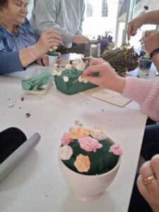 panie tworzą kompozycję z kwiatków z mydła