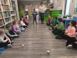 bibliotekarz wraz z chłopcem wykonują konkurencję, zwijają kłębek wełny