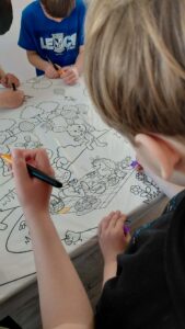 dzieci kolorują dużą kolorowankę wielkanocną