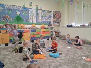 dzieci siedzą na dywanie i oglądają książeczki