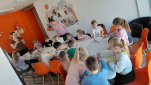 dzieci siedzą przy stole i czekają na rozpoczęcie zajęć
