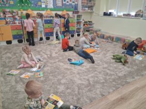 dzieci siedzą na dywanie i oglądają książeczki