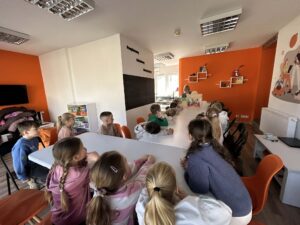 dzieci siedzą przy stole i czekają na rozpoczęcie zajęć