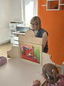 bibliotekarz czyta dzieciom bajkę w teatrzyku kamishibai