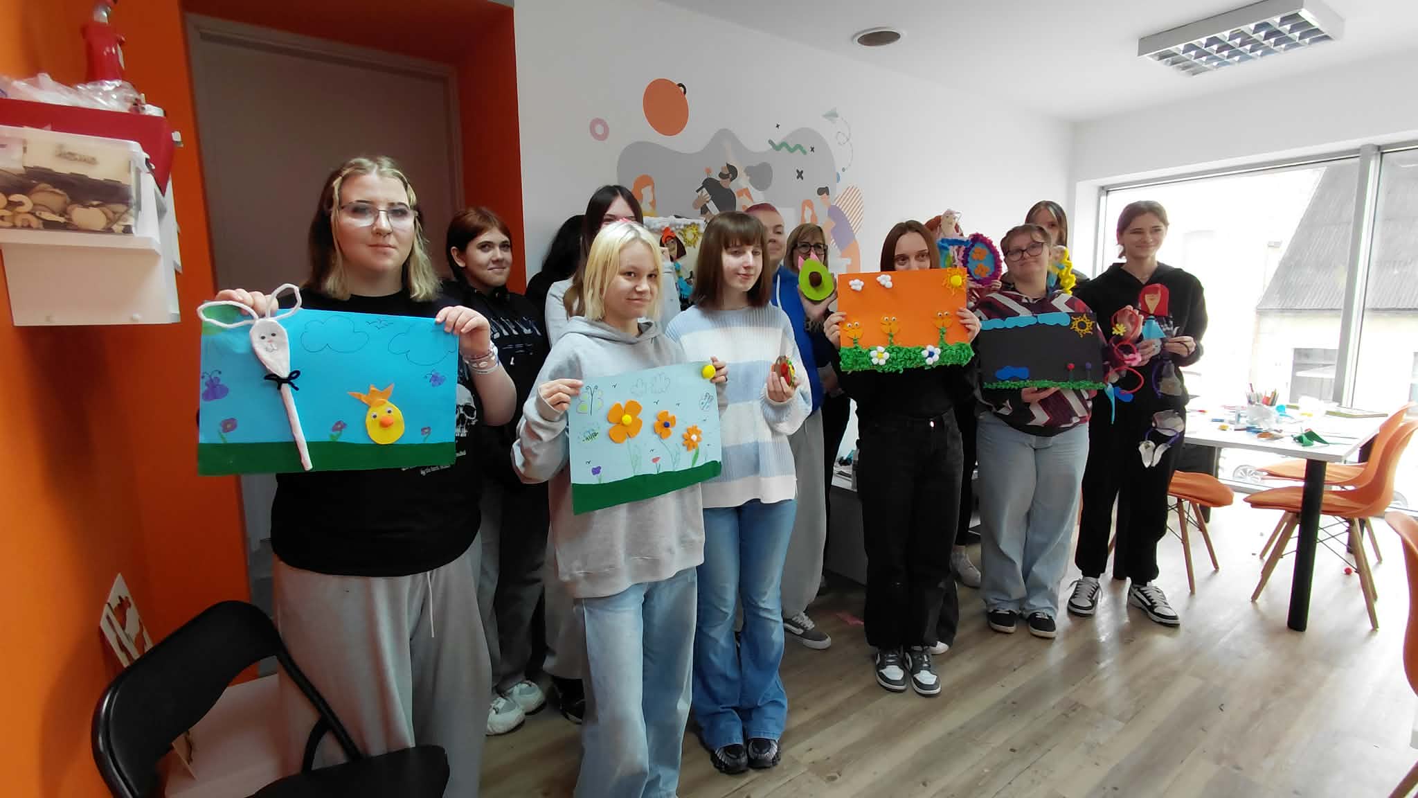 dziewczyny przy napisie pracownia orange prezentują swoje prace