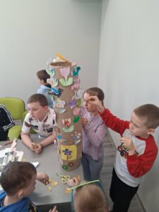dzieci przyklejają wiosenne dodatki na totem