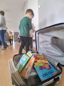 zdjęcie książek w walizce w tle dzieci, które wybierają książki