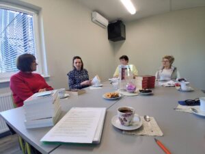 klubowicze siedzą przy stole i dyskutują o książce