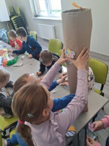 dziewczynka przykleja kwiatka na powstający totem