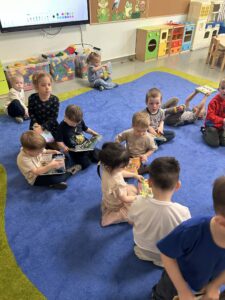 dzieci siedzą na dywanie i czytają książki