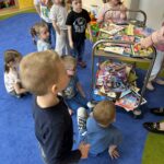 duża ilość książek, a obok dzieci, które czekają na moment wypożyczenia