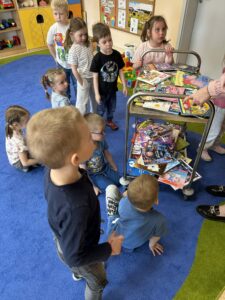 duża ilość książek, a obok dzieci, które czekają na moment wypożyczenia
