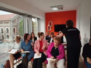uczestniczka rozdaje paniom kartki z zadaniami
