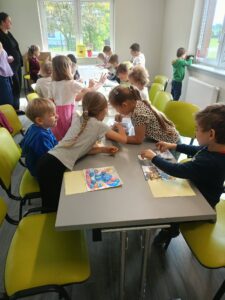 dzieci siedzą przy stołach i układają puzzle