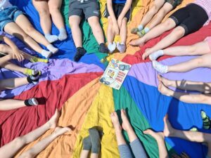 dzieci siedzą na chuście od klanzy i będą czytać książkę o Bolku i Lolku