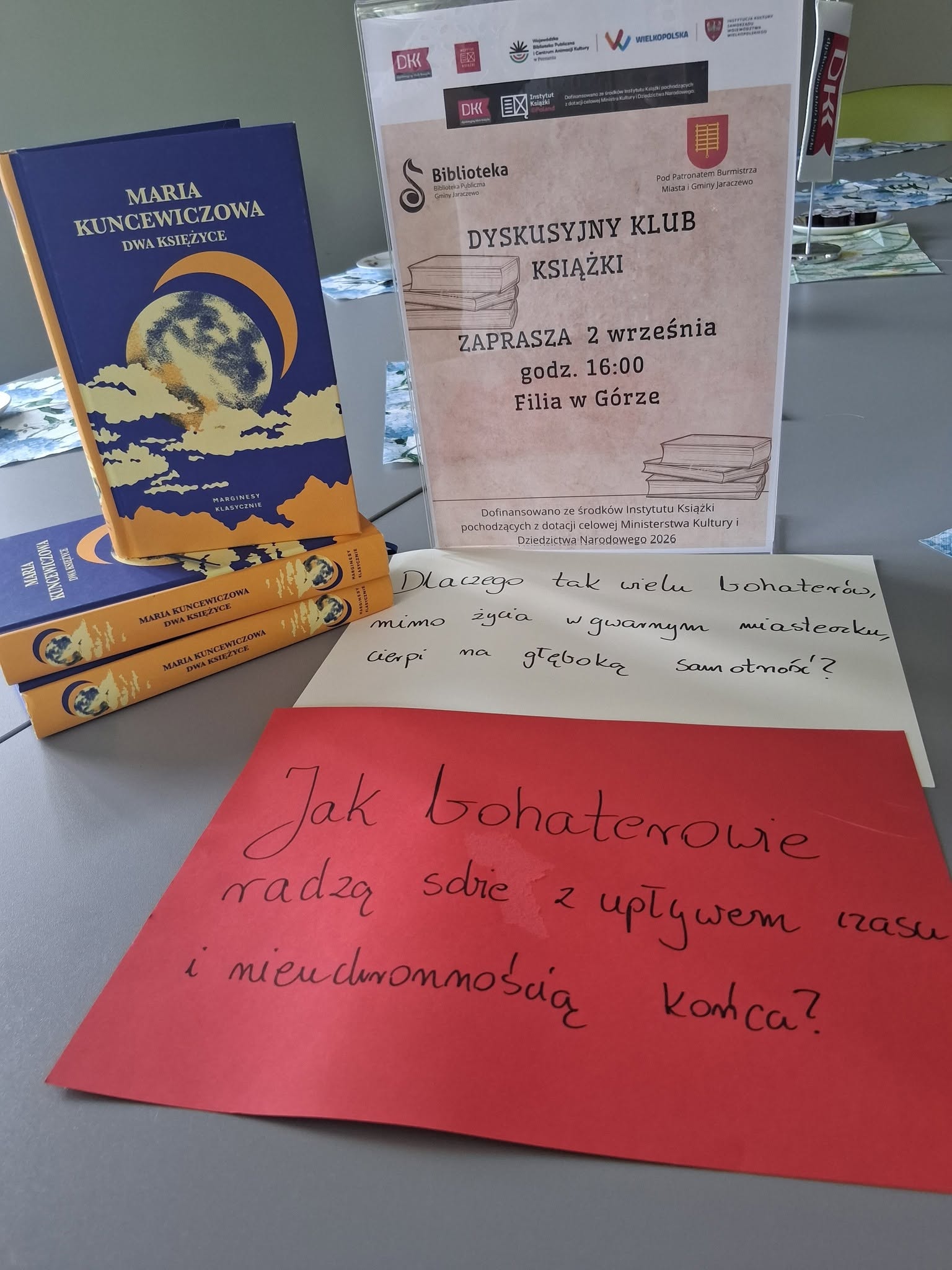 zdjęcie stosu książek i plakatu zapraszającego na dkk